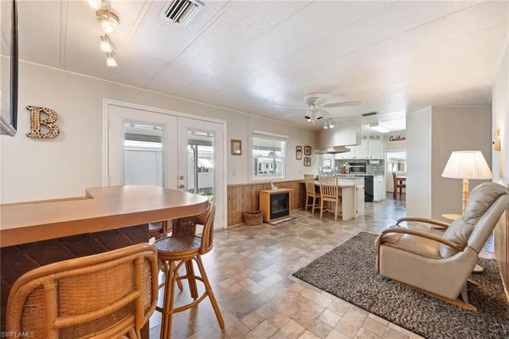 Living room featuring a ceiling fan, a wainscoted wall, stone finish flooring, a textured ceiling, and wood walls