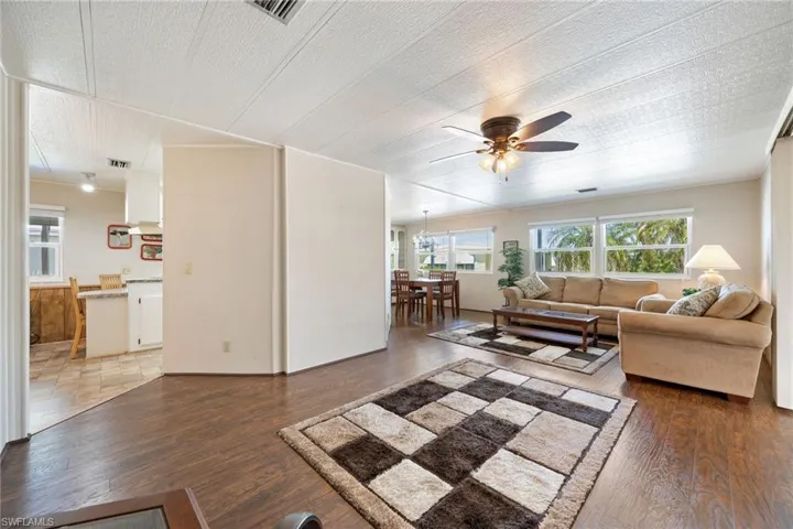 Living room featuring a ceiling fan, dark wood finished floors, a textured ceiling, and hanging lights