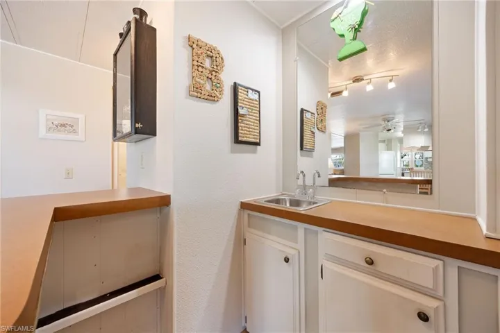 Bar with white cabinets, ceiling fan, light countertops, and a textured wall