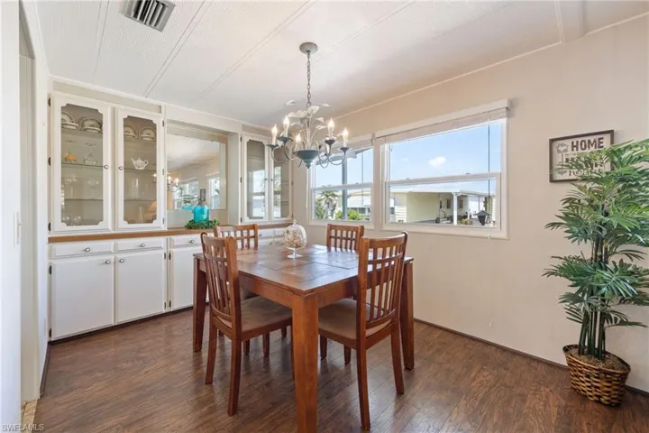 Dining space with dark wood-style floors and a chandelier