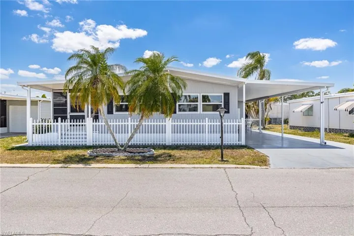 View of front of property featuring a fenced front yard, a carport, concrete driveway, and a porch