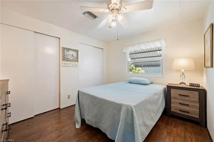 Bedroom with two closets, dark wood-style floors, and a ceiling fan