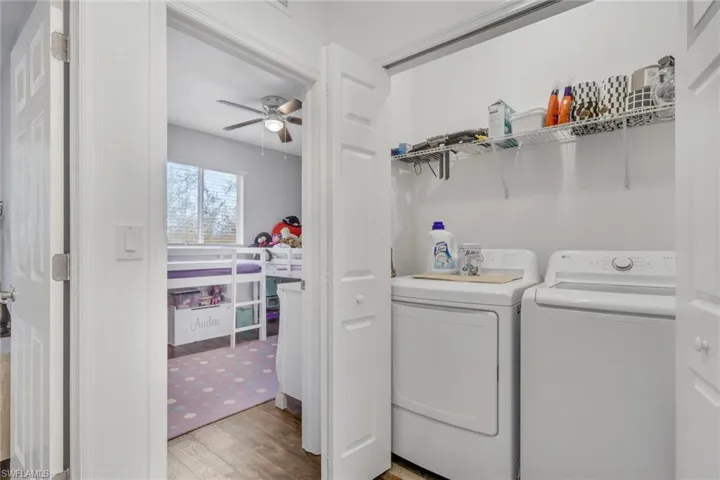 Laundry area with light wood-type flooring, washer and clothes dryer, and ceiling fan