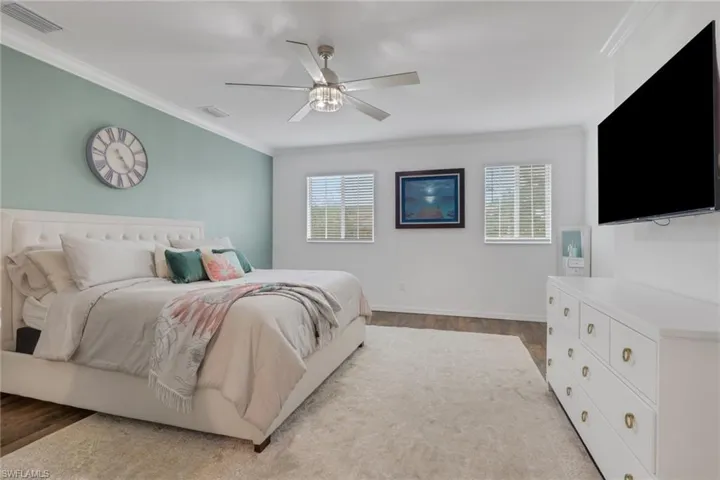 Bedroom with crown molding, dark wood-style floors, and a ceiling fan