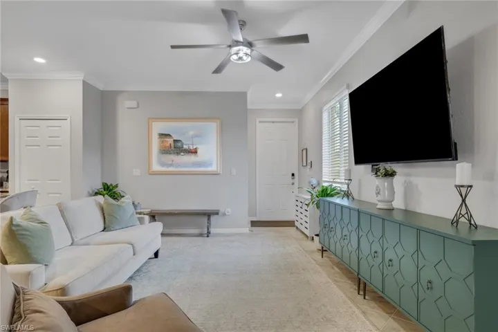Living area with ornamental molding, a ceiling fan, light tile patterned floors, and recessed lighting