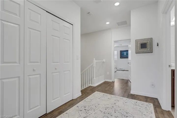 Hallway with an upstairs landing, recessed lighting, and dark wood finished floors