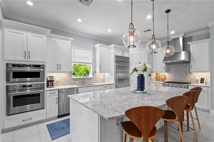 Kitchen with appliances with stainless steel finishes, wall chimney exhaust hood, ornamental molding, a center island, and decorative backsplash