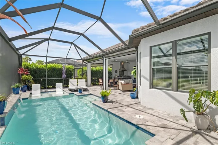 Swimming pool featuring a patio area, ceiling fan, exterior kitchen, and a lanai