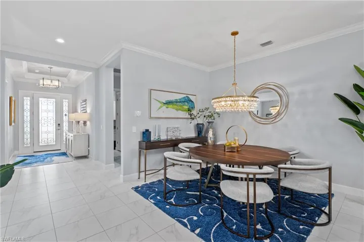 Dining room with a chandelier, crown molding, marble look tiles, and recessed lighting