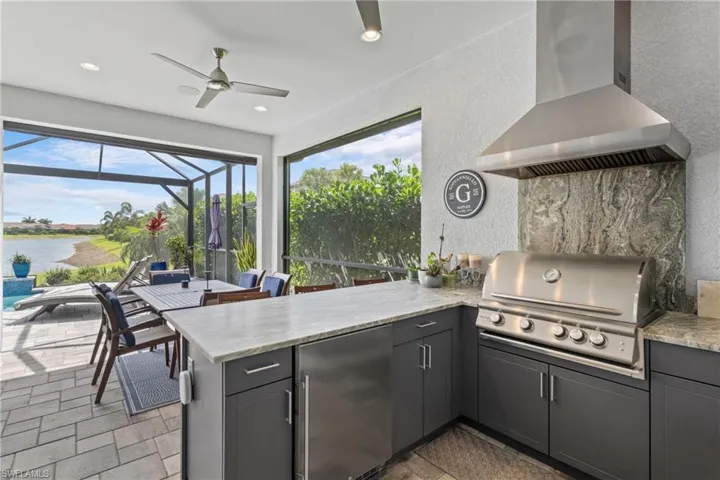 View of patio featuring an outdoor kitchen, a lanai, a water view, and ceiling fan