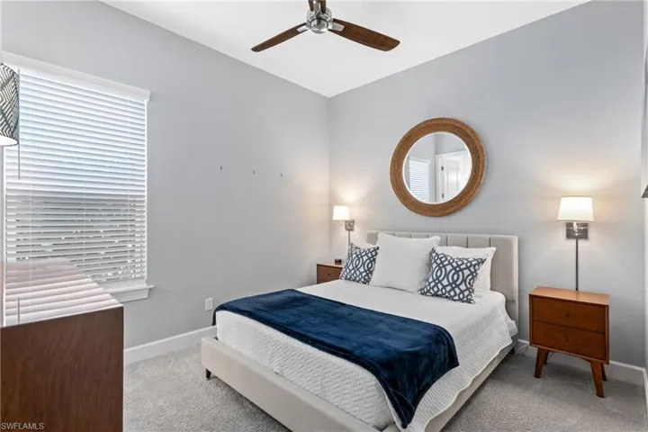Carpeted bedroom featuring vaulted ceiling and a ceiling fan