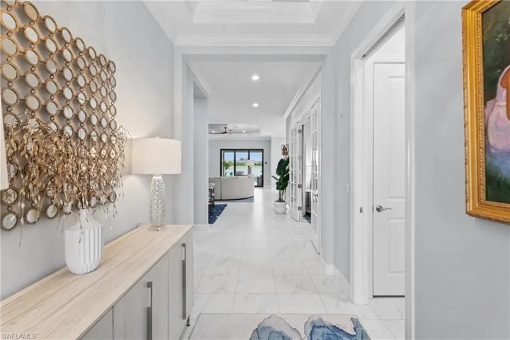 Hallway featuring light marble finish flooring, ornamental molding, and recessed lighting