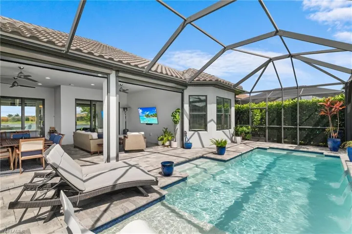 Swimming pool featuring a ceiling fan, a patio, an outdoor hangout area, and glass enclosure