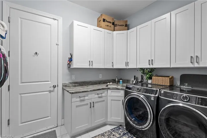 Laundry area featuring cabinet space, washing machine and clothes dryer, and light tile patterned floors