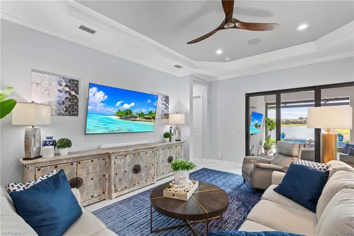 Living room with a tray ceiling, crown molding, a ceiling fan, and recessed lighting