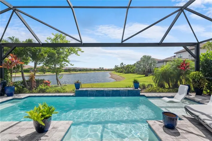 Outdoor pool with a water view, a lanai, a lawn, and a patio area
