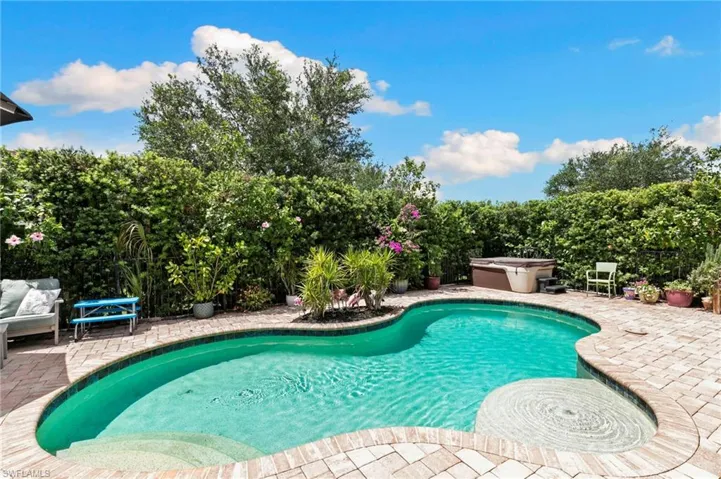 Freeform swimming pool with integrated spa and paver surround