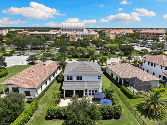 Expansive backyard featuring a covered patio, paved outdoor area, mature perimeter landscaping, and a manicured lawn