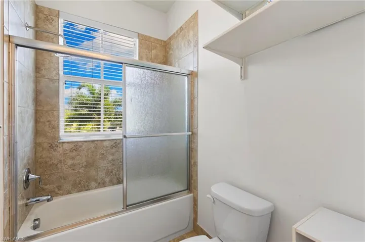 Bath #3 Bathtub with sliding glass shower doors, chrome fixtures, and a tiled surround