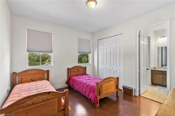 Bedroom #3 featuring wood-finish flooring, two windows with blinds, a bi-fold closet, and a ceiling-mounted light fixture