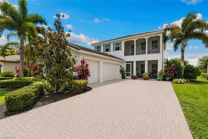 Two-story residence featuring a three-car garage and mature landscaping