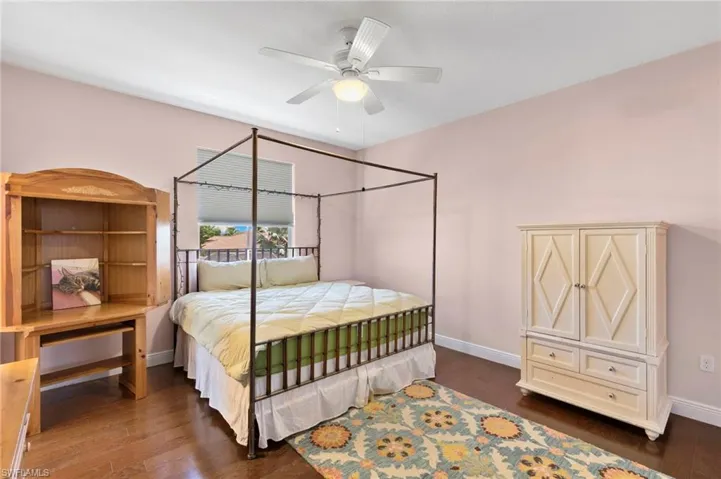 Bedroom #4 featuring wood-finish flooring, a ceiling fan with integrated lighting, and a single window with blinds