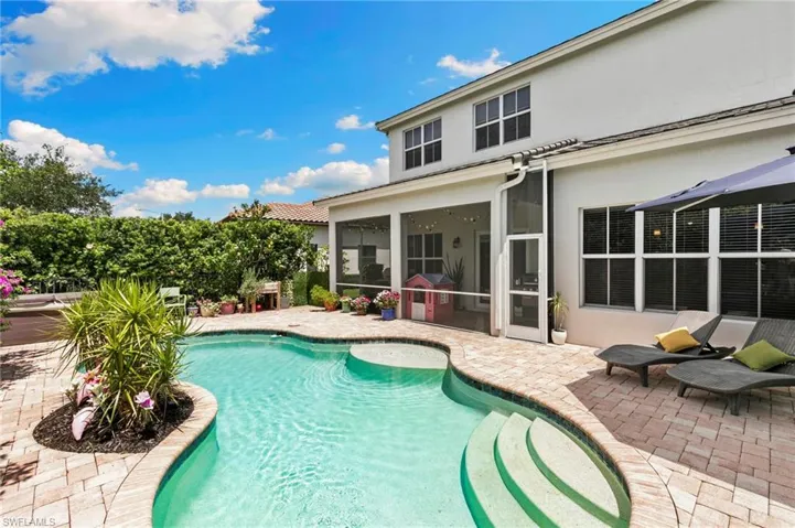 swimming pool with integrated steps, surrounded by brick paver decking and fountain