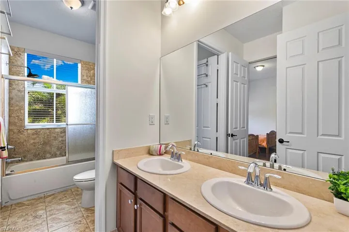 Bathroom #3 featuring a dual-sink vanity with a beige countertop, wood-finish cabinetry, and chrome fixtures