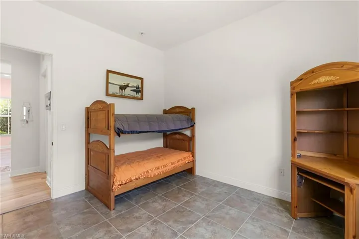 1st floor Bedroom #2 featuring ceramic tile flooring, neutral wall paint, and a doorway opening to a wood-finish floor