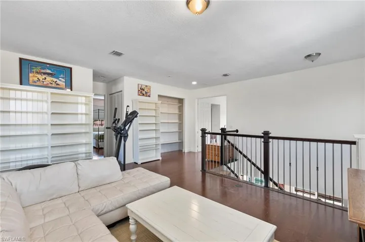 Bonus Room space featuring rich wood-finish flooring and a dark wood and metal baluster railing