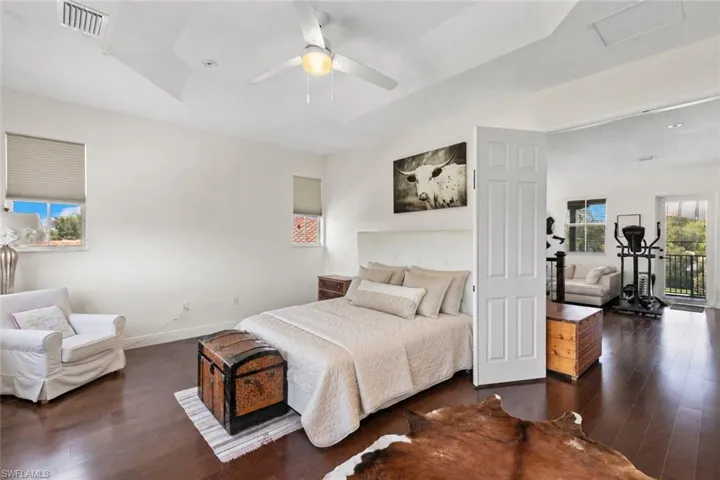 Spacious Primary Bedroom wood-finish flooring, white walls, and a recessed ceiling