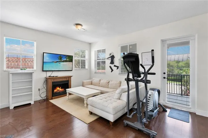 Interior space featuring wood-finish flooring, white walls, and multiple windows with blinds