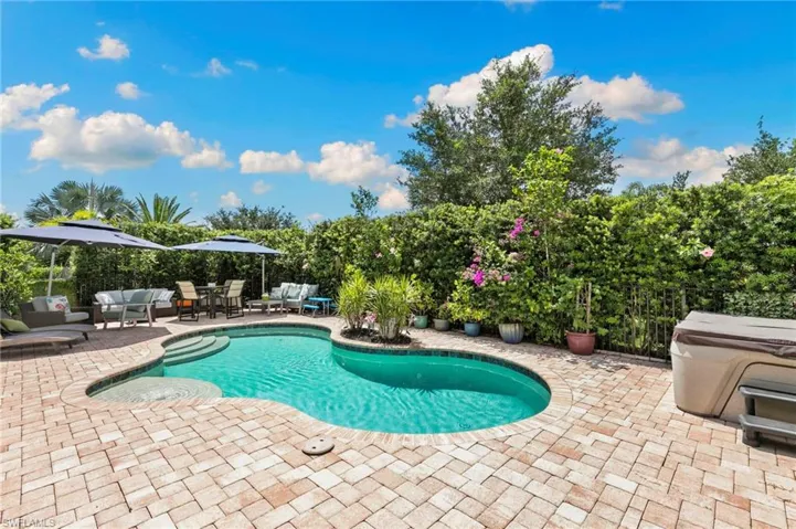 Kidney-shaped pool with integrated spa and paver decking