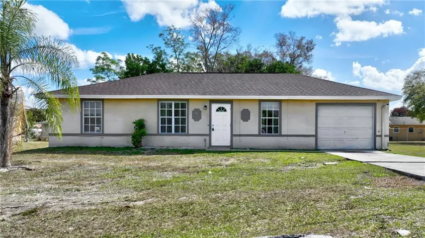 Ranch-style house featuring stucco siding, a front lawn, an attached garage, and roof with shingles