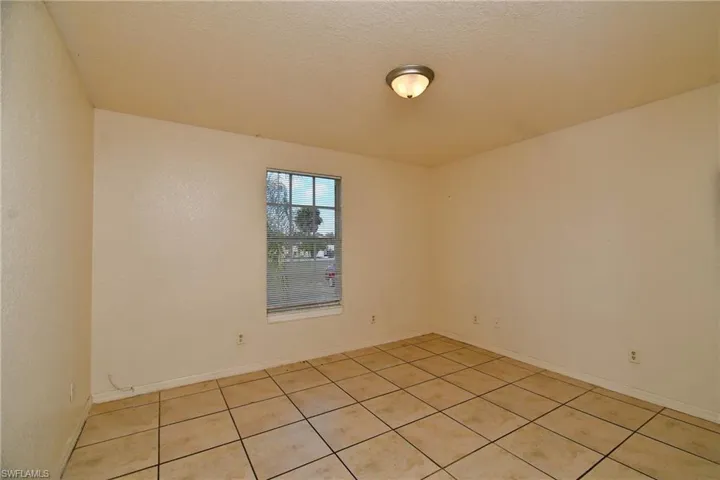 Empty room featuring a textured ceiling and light tile patterned flooring