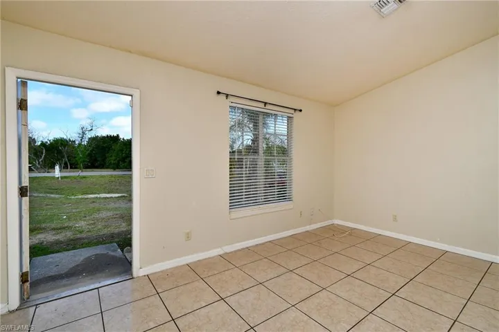 Empty room featuring vaulted ceiling and light tile patterned floors