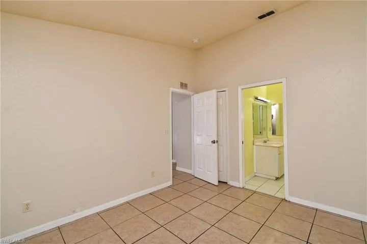 Unfurnished bedroom with light tile patterned floors and ensuite bathroom