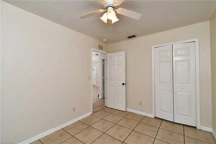 Unfurnished bedroom featuring ceiling fan, light tile patterned floors, and a closet