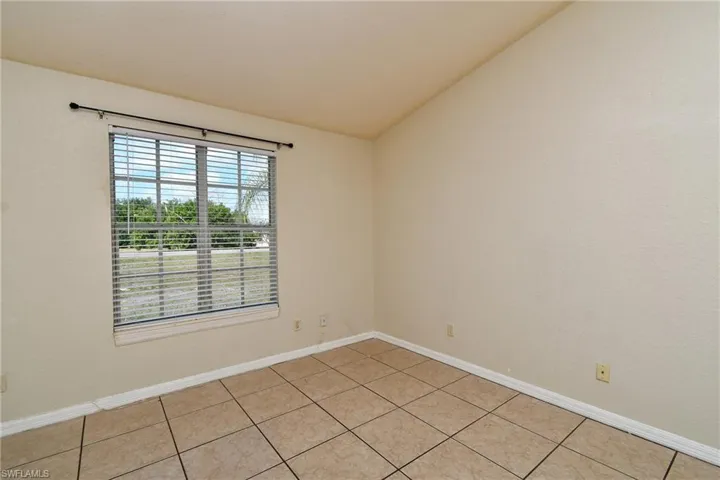 Unfurnished room with lofted ceiling and light tile patterned floors