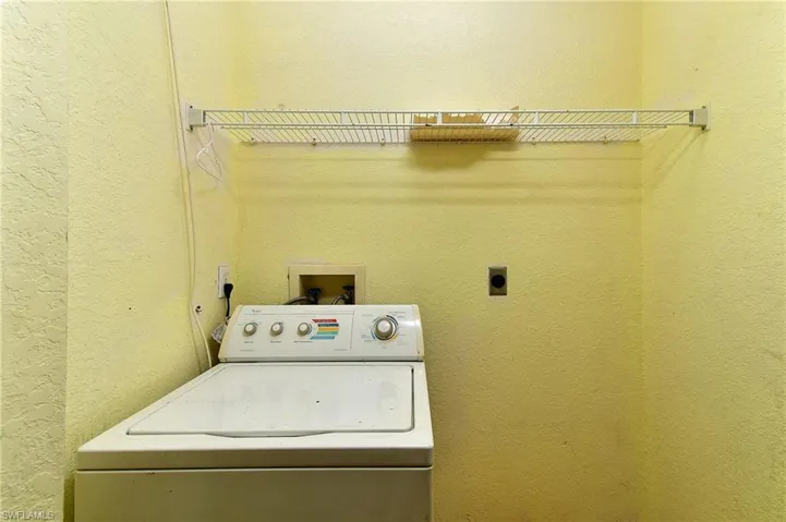 Laundry area with a textured wall and washer / dryer