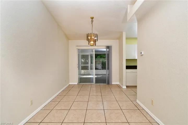 Unfurnished dining area with a textured wall, hanging lights, and light tile patterned floors