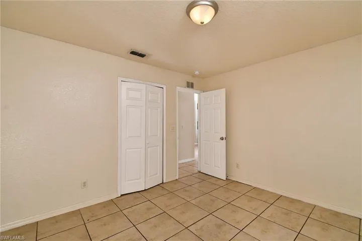 Unfurnished bedroom with a closet, light tile patterned flooring, and a textured ceiling