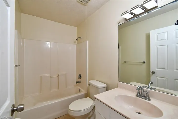 Full bath with vanity, a textured ceiling, and  shower combination