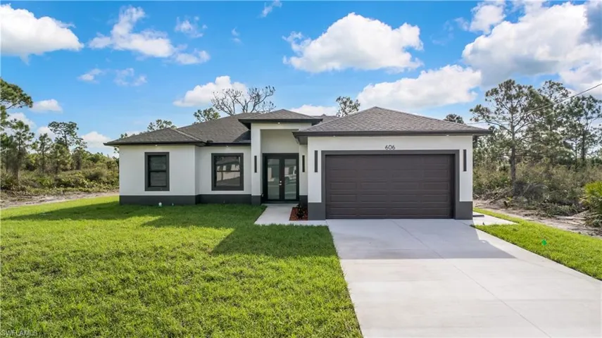 Prairie-style home with stucco siding, driveway, a garage, a front lawn, and a shingled roof