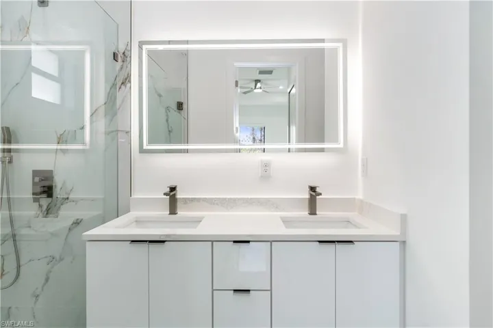 Bathroom with double vanity, a marble finish shower, and a ceiling fan