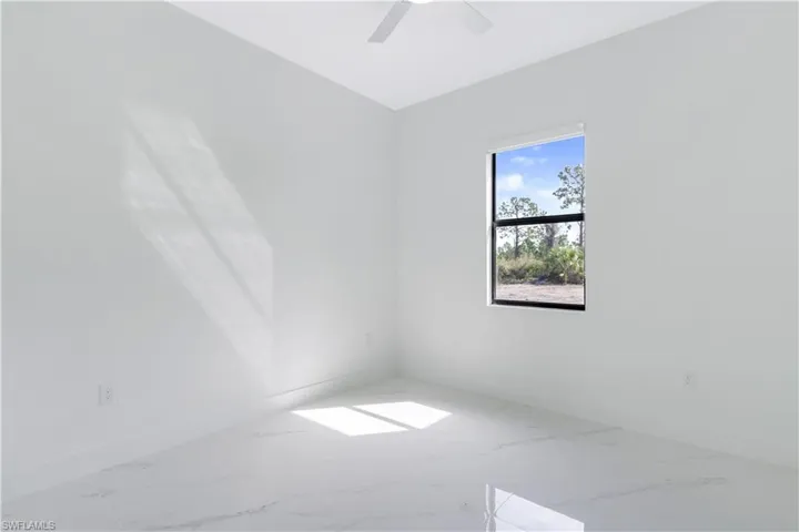 Empty room featuring marble finish floors and ceiling fan