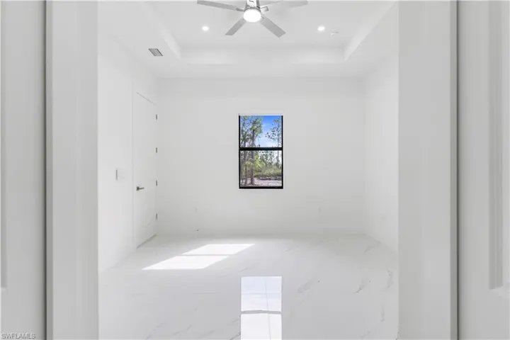 Spare room featuring light marble finish flooring, a tray ceiling, a ceiling fan, and recessed lighting
