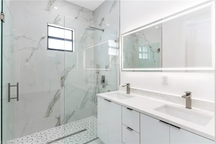 Full bathroom featuring double vanity and a marble finish shower