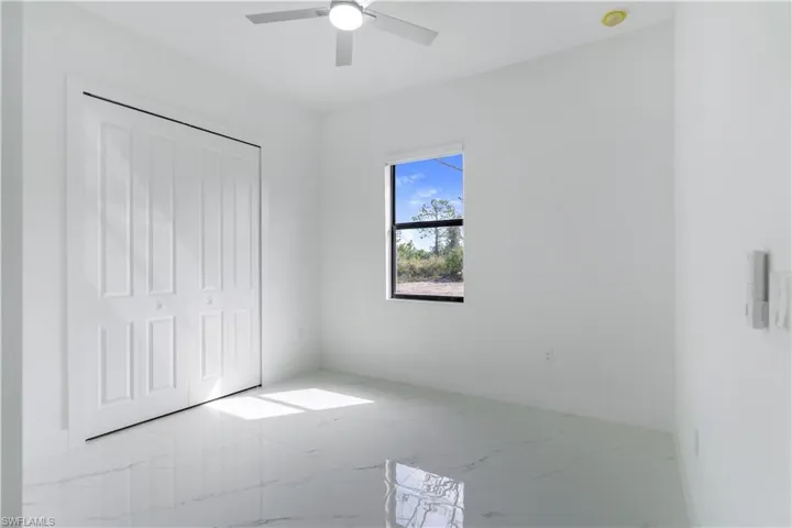 Unfurnished bedroom featuring light marble finish flooring, a closet, and a ceiling fan