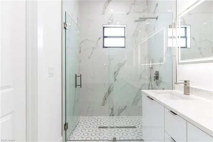 Full bath featuring vanity and a marble finish shower